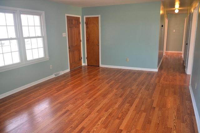 spare room featuring dark wood-style floors, visible vents, and baseboards