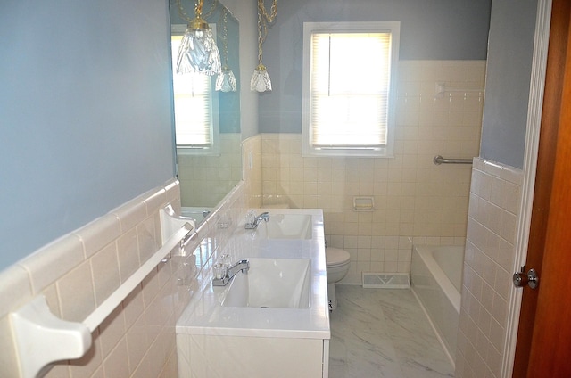 bathroom featuring toilet, tile walls, plenty of natural light, and marble finish floor