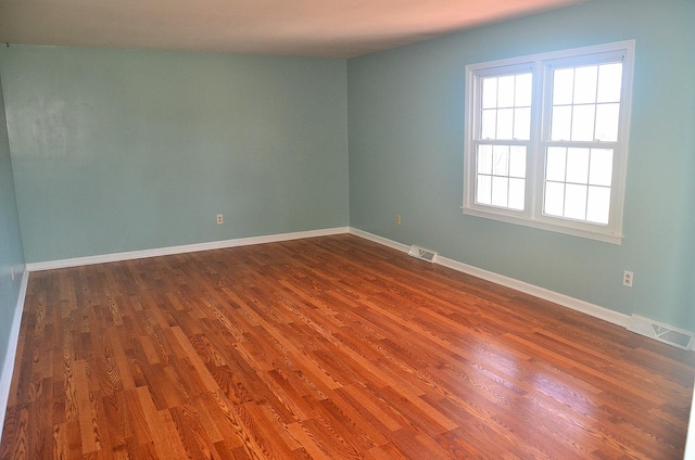 unfurnished room featuring visible vents, baseboards, and dark wood-type flooring