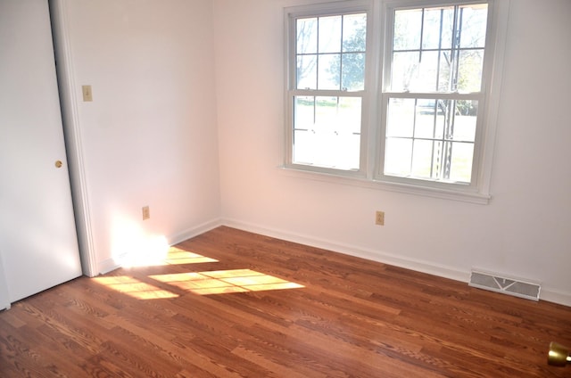 empty room with visible vents, baseboards, and wood finished floors