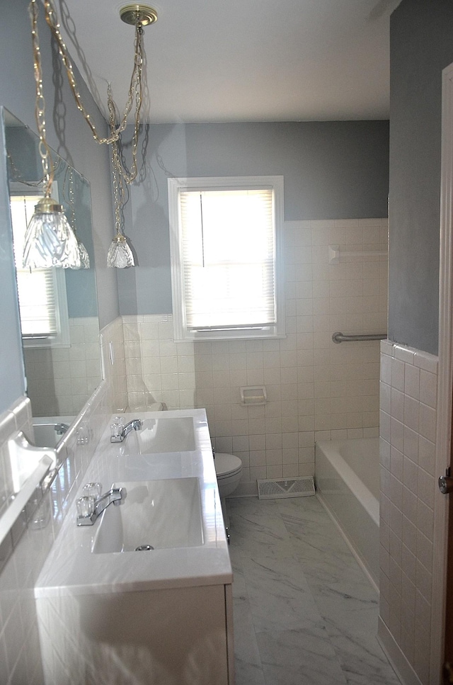 bathroom featuring vanity, a tub, tile walls, toilet, and marble finish floor