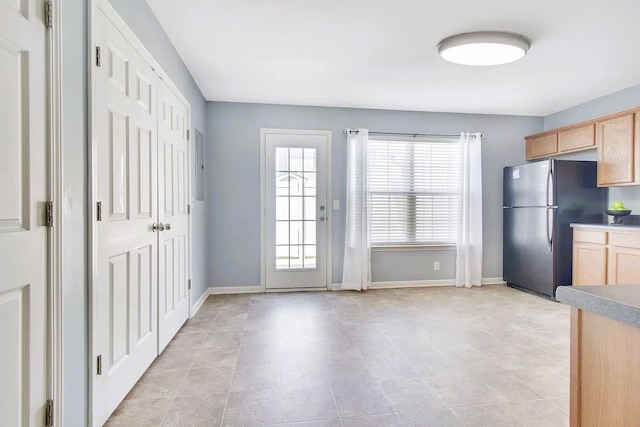 kitchen with baseboards, a healthy amount of sunlight, light brown cabinetry, and freestanding refrigerator