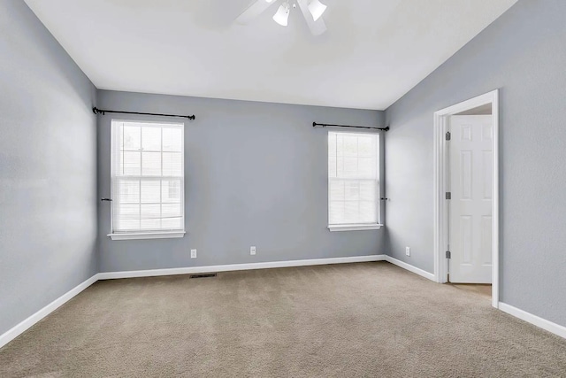 empty room with visible vents, a healthy amount of sunlight, carpet, and ceiling fan