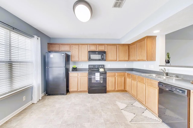 kitchen featuring visible vents, black appliances, light brown cabinets, a sink, and baseboards