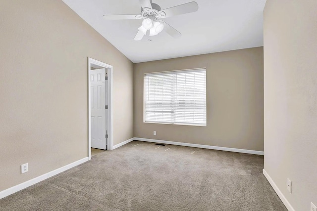 carpeted spare room with vaulted ceiling, baseboards, and ceiling fan