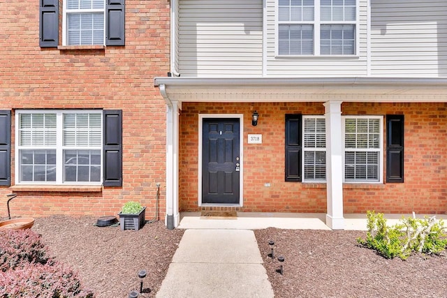 property entrance featuring brick siding and covered porch