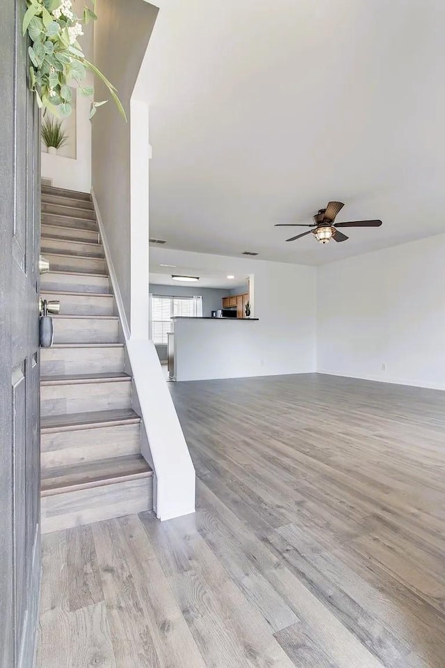 stairs with wood finished floors and a ceiling fan