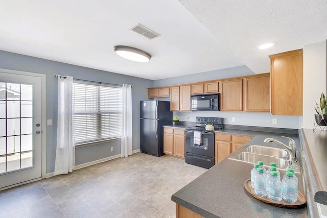 kitchen with black appliances, dark countertops, visible vents, and a sink