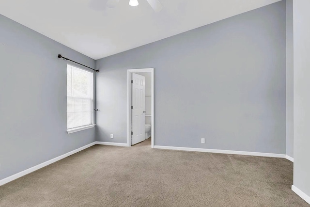 carpeted empty room with lofted ceiling, baseboards, and ceiling fan