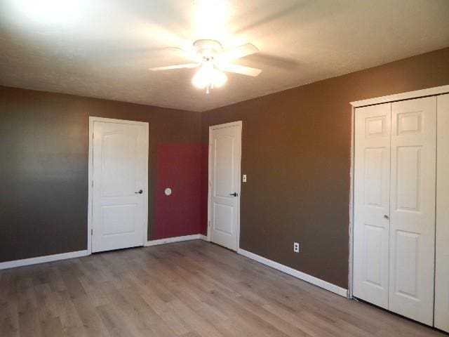 unfurnished bedroom featuring a closet, light wood-style flooring, and baseboards