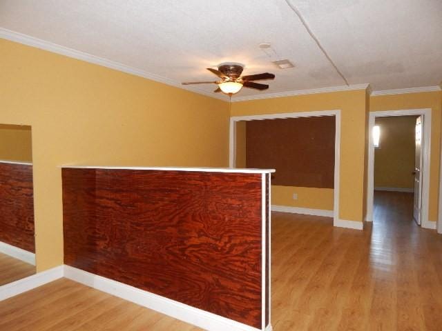 unfurnished room featuring baseboards, light wood-type flooring, a ceiling fan, and ornamental molding