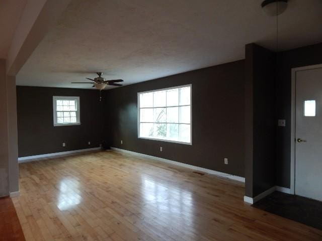 interior space featuring wood finished floors, baseboards, and ceiling fan