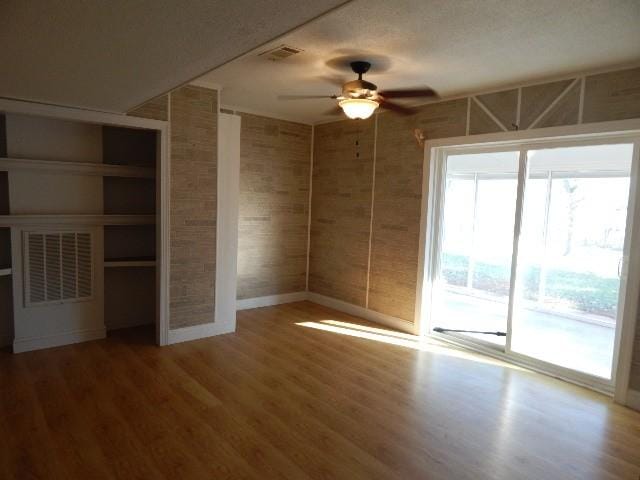 unfurnished room with visible vents, baseboards, a ceiling fan, and wood finished floors