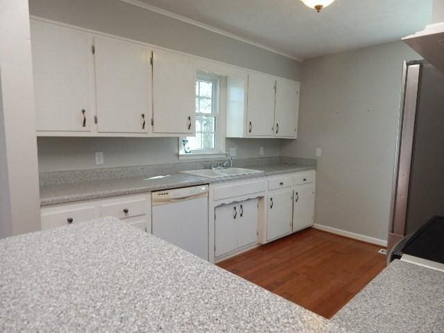 kitchen featuring wood finished floors, white cabinetry, a sink, light countertops, and dishwasher