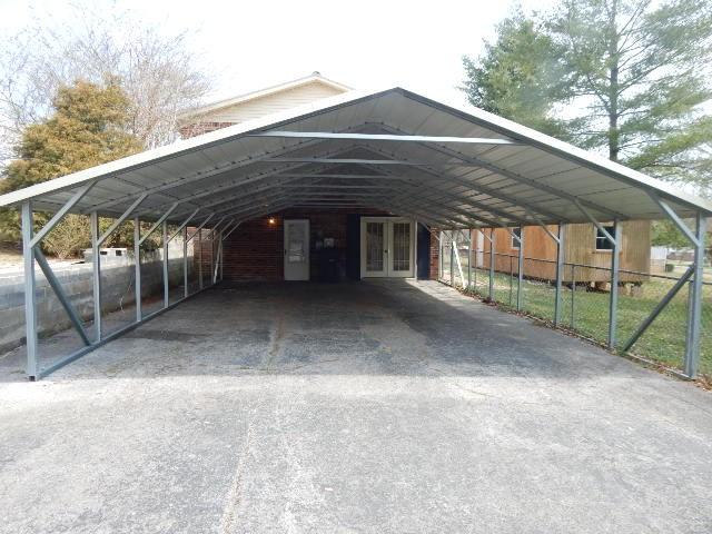 view of parking featuring a detached carport, french doors, and fence