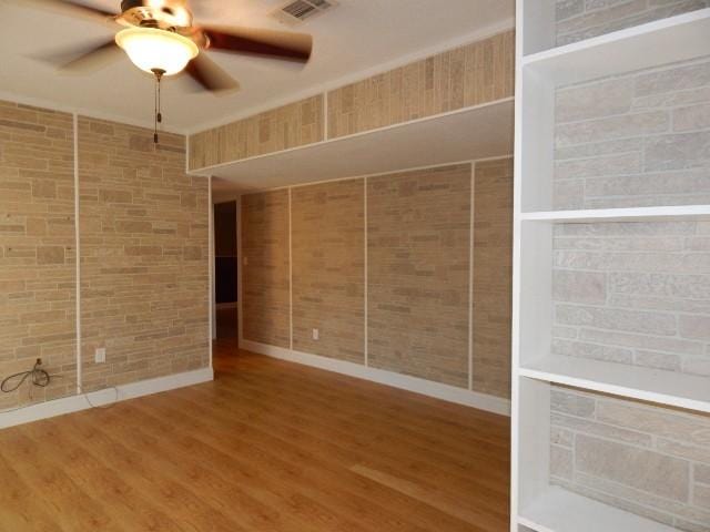 empty room with visible vents, ceiling fan, and wood finished floors