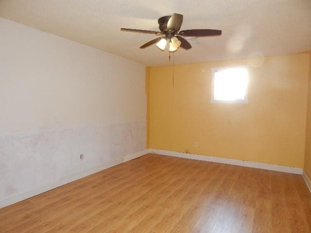 empty room with ceiling fan, baseboards, and light wood-style floors