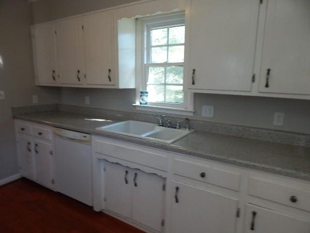 kitchen featuring a sink, dark wood-style flooring, white dishwasher, and white cabinetry