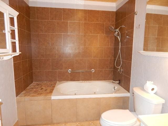 bathroom with tiled shower / bath combo, toilet, and vanity