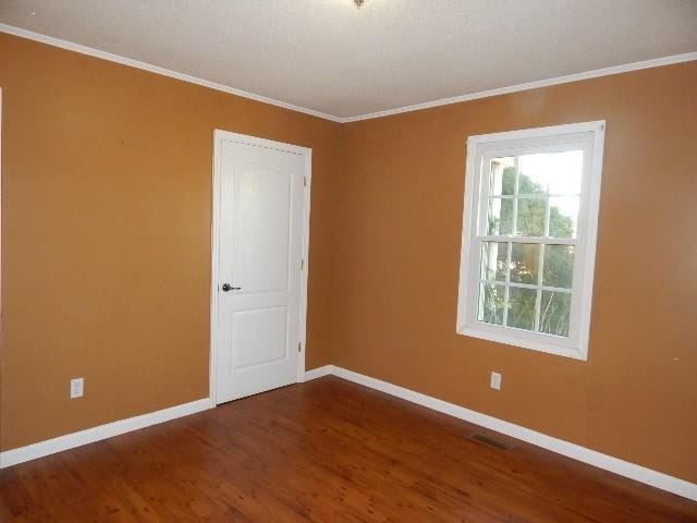 unfurnished room with wood finished floors, baseboards, and ornamental molding