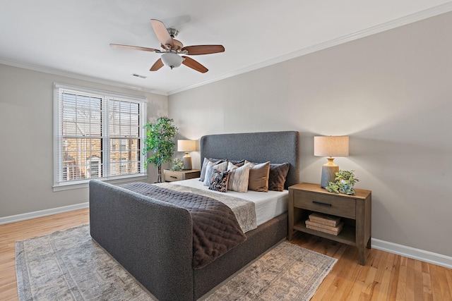 bedroom with baseboards, wood finished floors, visible vents, and ornamental molding