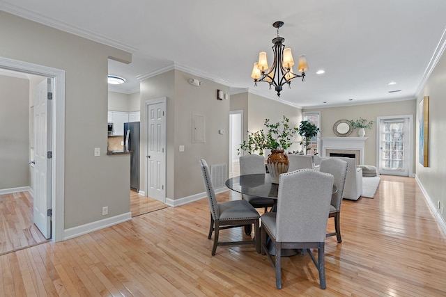 dining room with a chandelier, light wood-style flooring, a fireplace, and baseboards