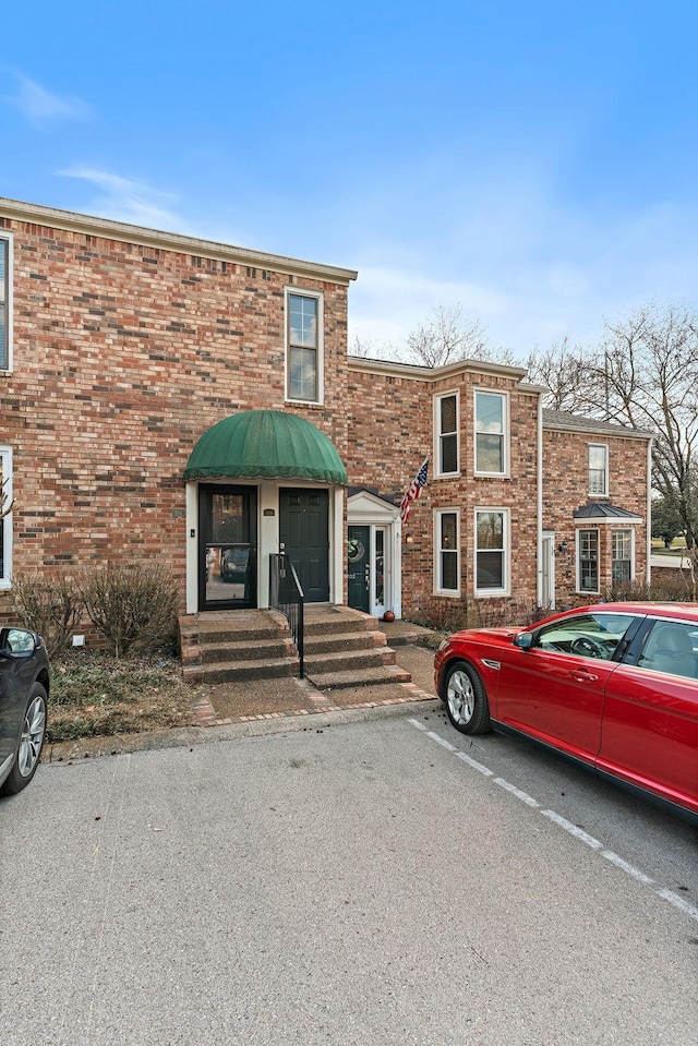 townhome / multi-family property featuring uncovered parking and brick siding