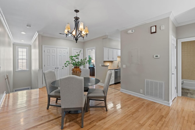 dining room featuring light wood finished floors, visible vents, baseboards, a chandelier, and ornamental molding