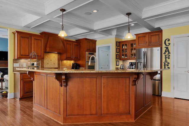 kitchen featuring a breakfast bar area, custom range hood, glass insert cabinets, and stainless steel appliances