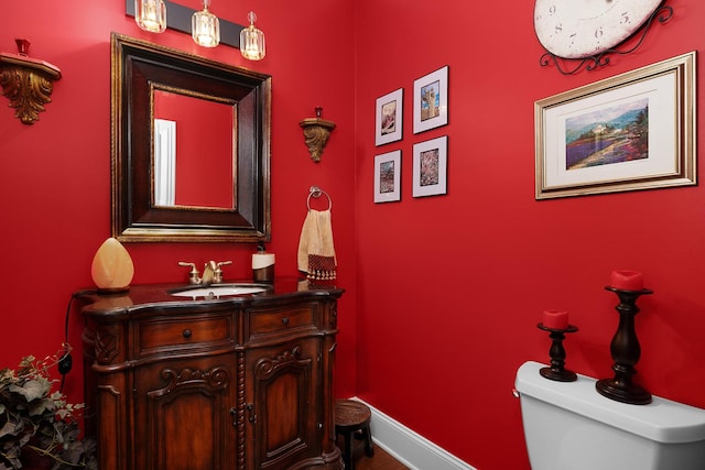 half bathroom with toilet, vanity, and baseboards