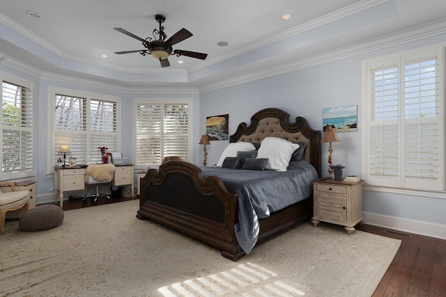 bedroom featuring ornamental molding, baseboards, a tray ceiling, and wood-type flooring