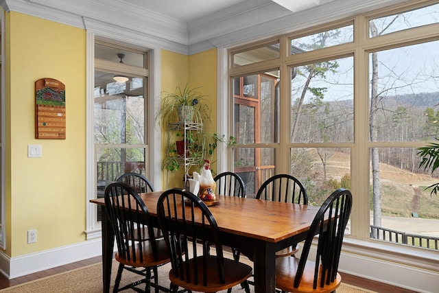 dining room with plenty of natural light, ornamental molding, baseboards, and wood finished floors