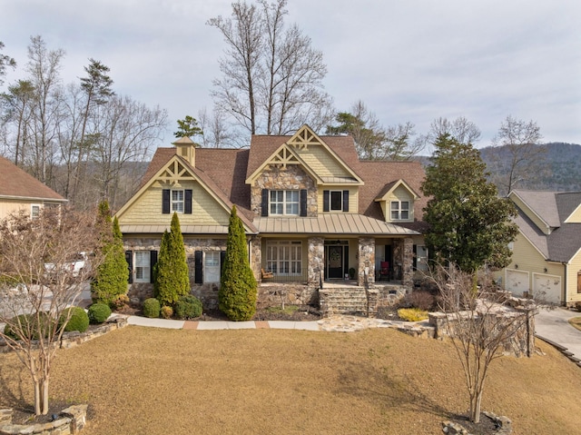 craftsman house featuring stone siding, a porch, a front yard, and a standing seam roof