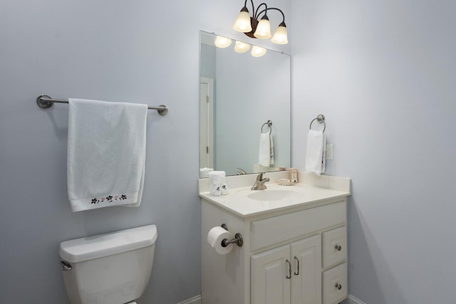 half bathroom featuring toilet, vanity, and baseboards