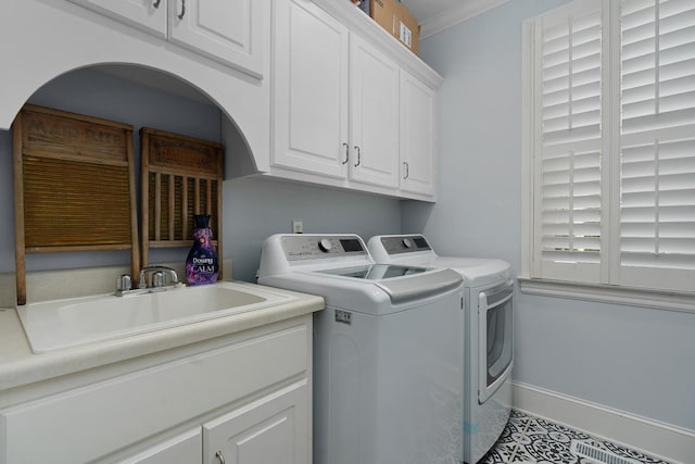 laundry area with ornamental molding, a sink, cabinet space, baseboards, and washing machine and clothes dryer