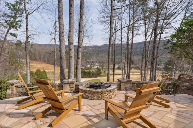 view of patio with a forest view and an outdoor fire pit