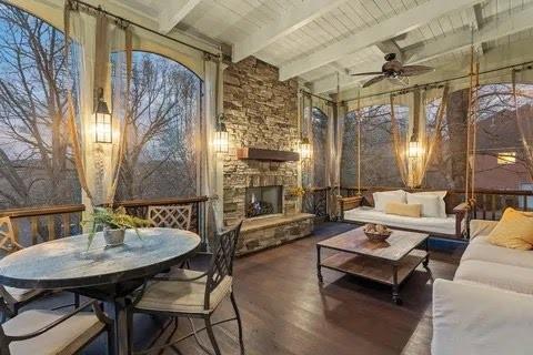 sunroom / solarium featuring wood ceiling, beam ceiling, an outdoor stone fireplace, and a ceiling fan