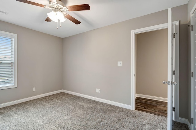 carpeted empty room featuring visible vents, baseboards, and a ceiling fan