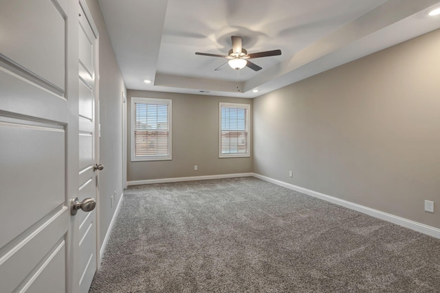 carpeted empty room featuring a raised ceiling, recessed lighting, a ceiling fan, and baseboards