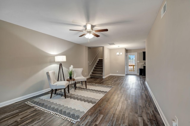 sitting room with dark wood-type flooring, stairway, visible vents, and baseboards