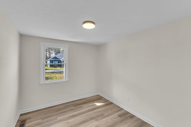 empty room featuring visible vents, light wood-style flooring, and baseboards