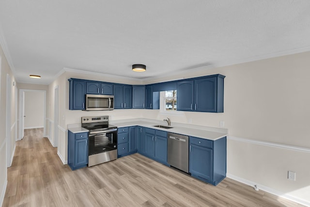 kitchen with light wood finished floors, blue cabinetry, a sink, stainless steel appliances, and light countertops