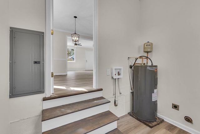 stairs featuring electric water heater, baseboards, ornamental molding, electric panel, and wood finished floors