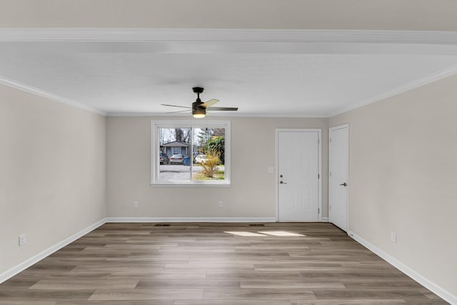 unfurnished room with crown molding, baseboards, and wood finished floors