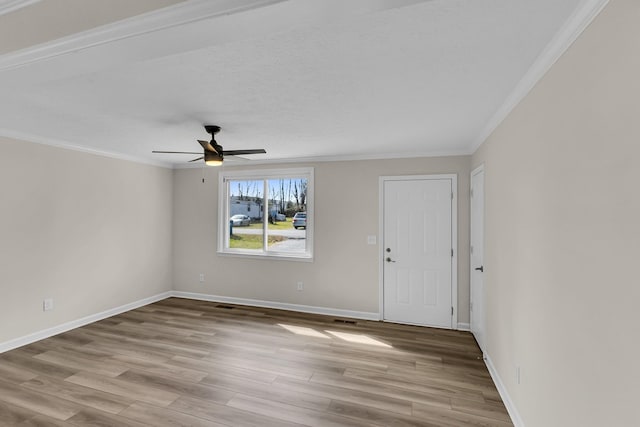 unfurnished room with visible vents, ceiling fan, baseboards, ornamental molding, and wood finished floors