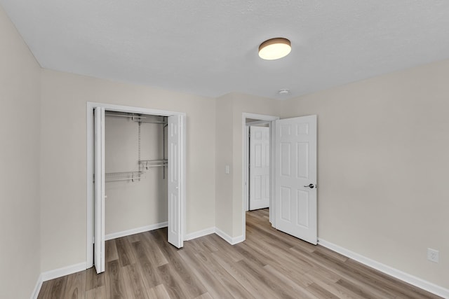 unfurnished bedroom featuring a closet, baseboards, and light wood-style floors