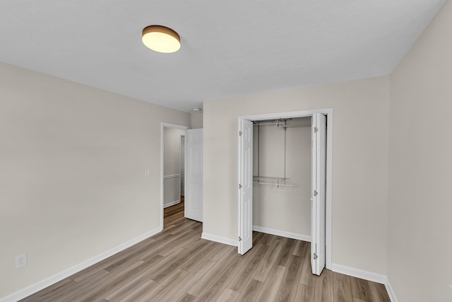 unfurnished bedroom with a closet, baseboards, and light wood-style floors