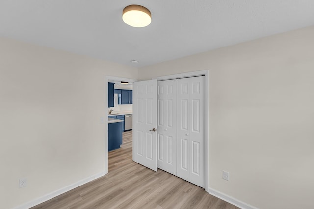 bedroom with light wood-style flooring, baseboards, and a closet