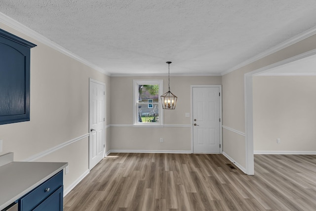 unfurnished dining area with a notable chandelier, wood finished floors, baseboards, and a textured ceiling