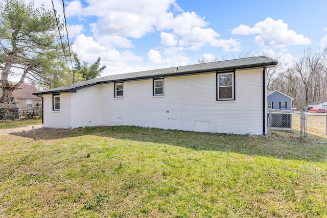 rear view of property featuring crawl space, a lawn, brick siding, and fence